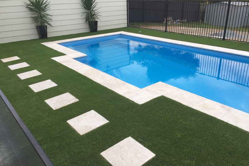 Luxury poolside remodel with artificial turf borders and modern large-format paving