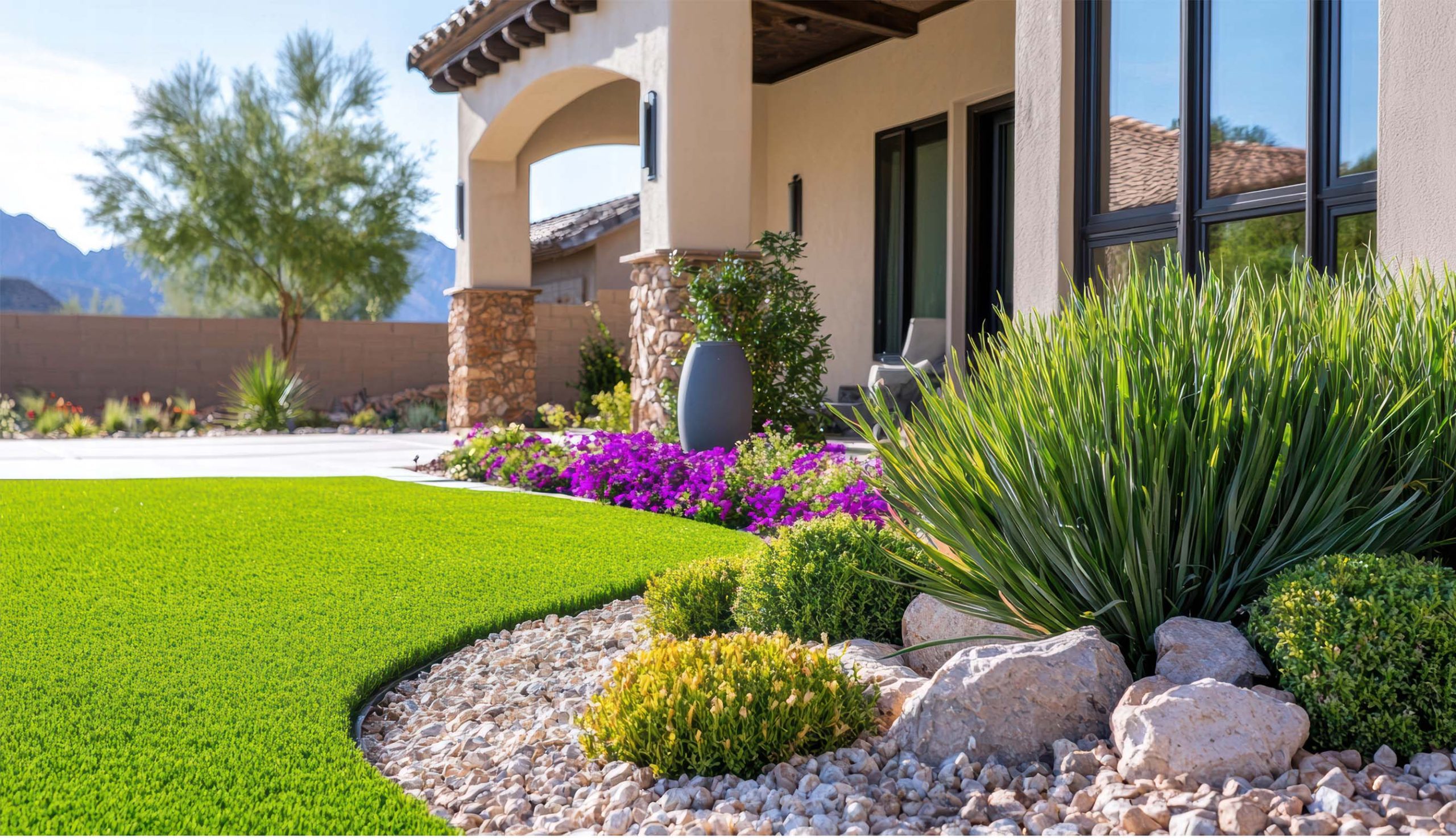 Resort style poolside backyard design with synthetic grass borders, modern lounge seating, and a luxury pool in Summerlin NV
