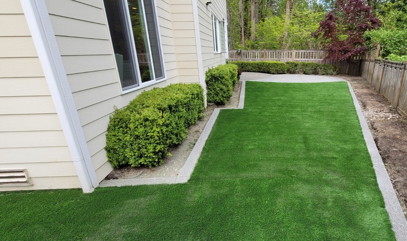 Residential side yard with freshly installed artificial turf and clean stone border