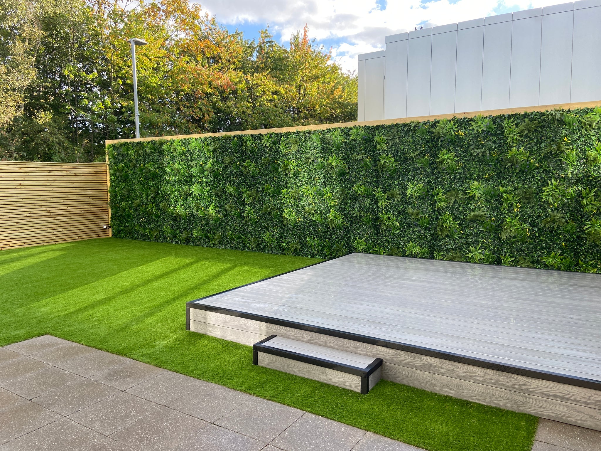 Vertical green wall panel close-up showing lush artificial foliage texture